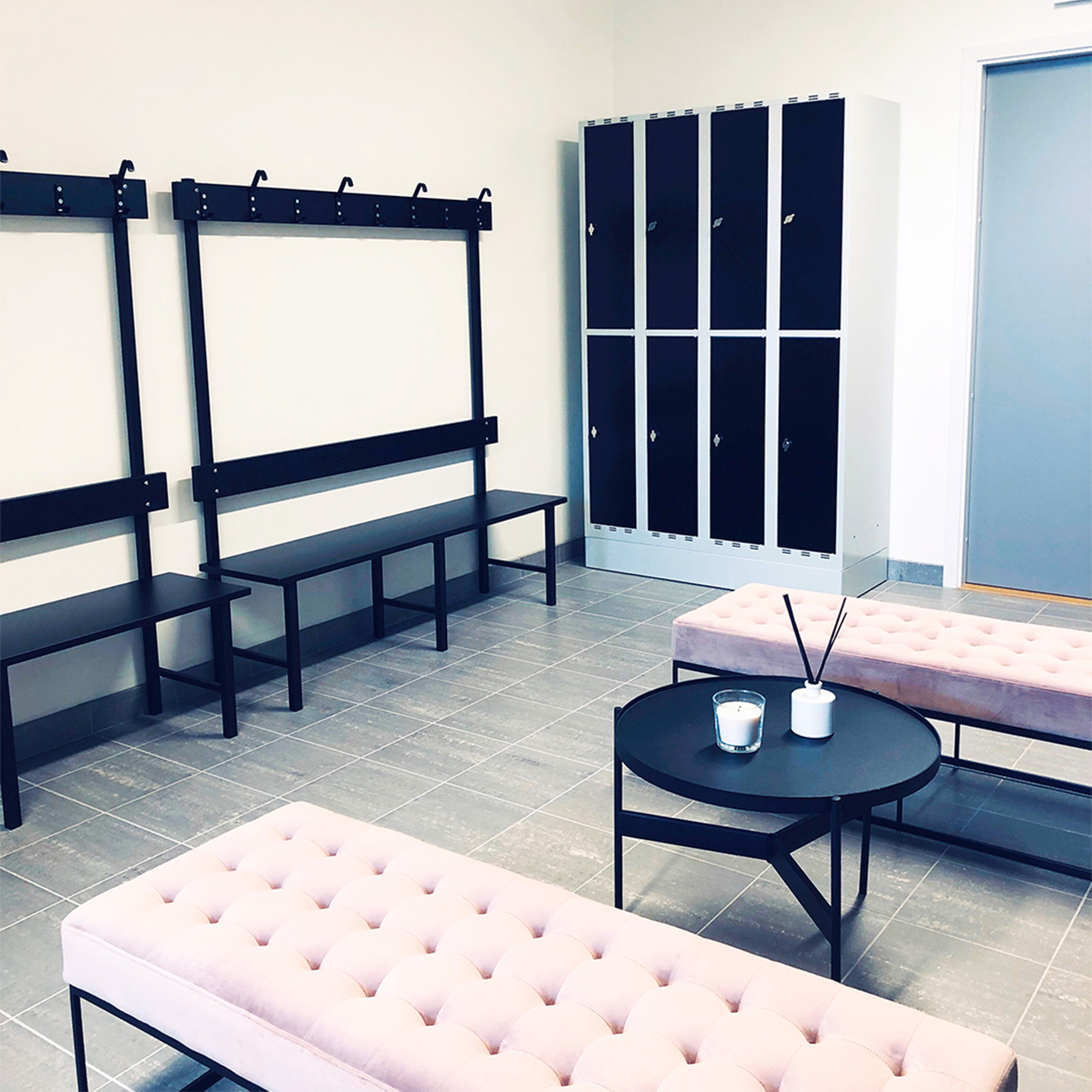 Sittbänk Enkelsektion 1000-2000 mm Svart i omklädningsrum med svart laminat och kroklist för klädförvaring.