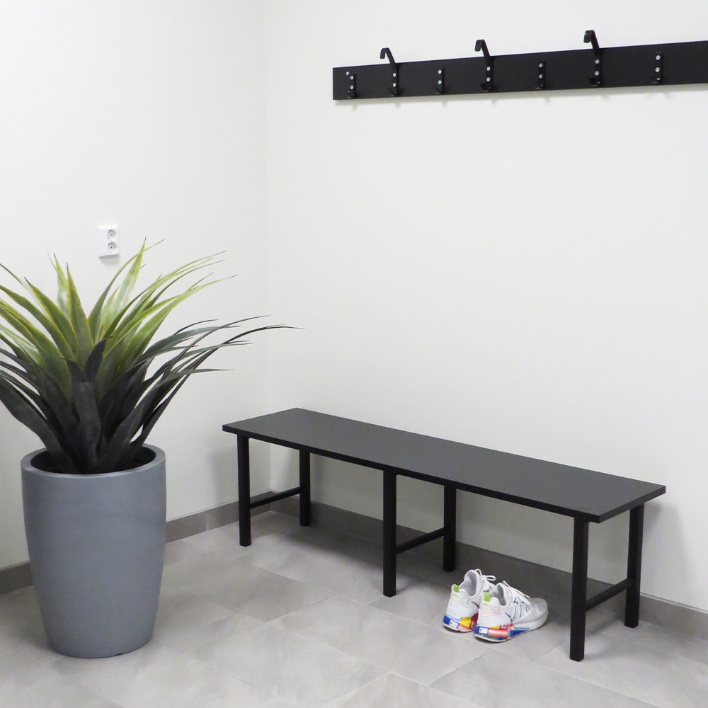 Sittbänk 1000-2000 mm Svart med stabil stålkonstruktion och svart laminatsits i modern hallmiljö.