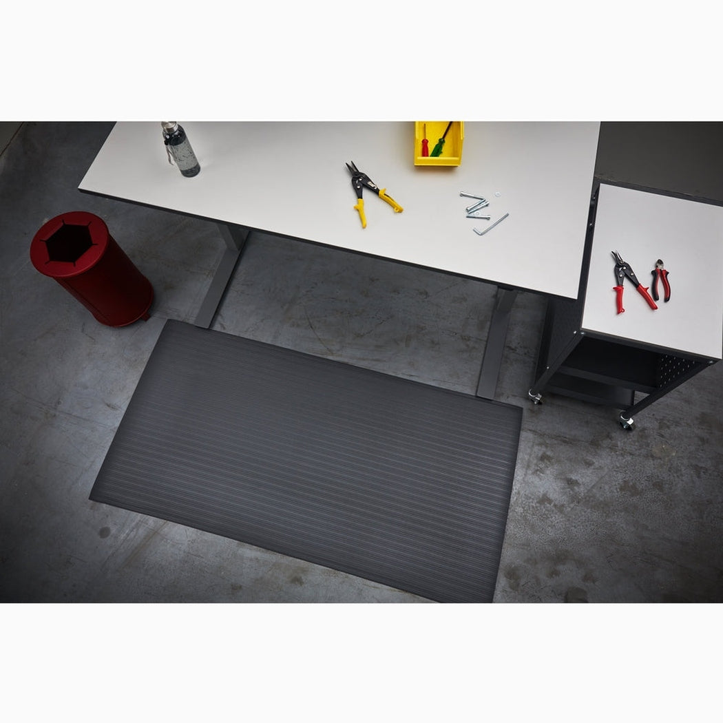 Arbetsplatsmatta Senso Ribb Plus i svart vinyl med ribbad yta, extra slitskikt och halkfri säkerhet för industriella arbetsplatser.